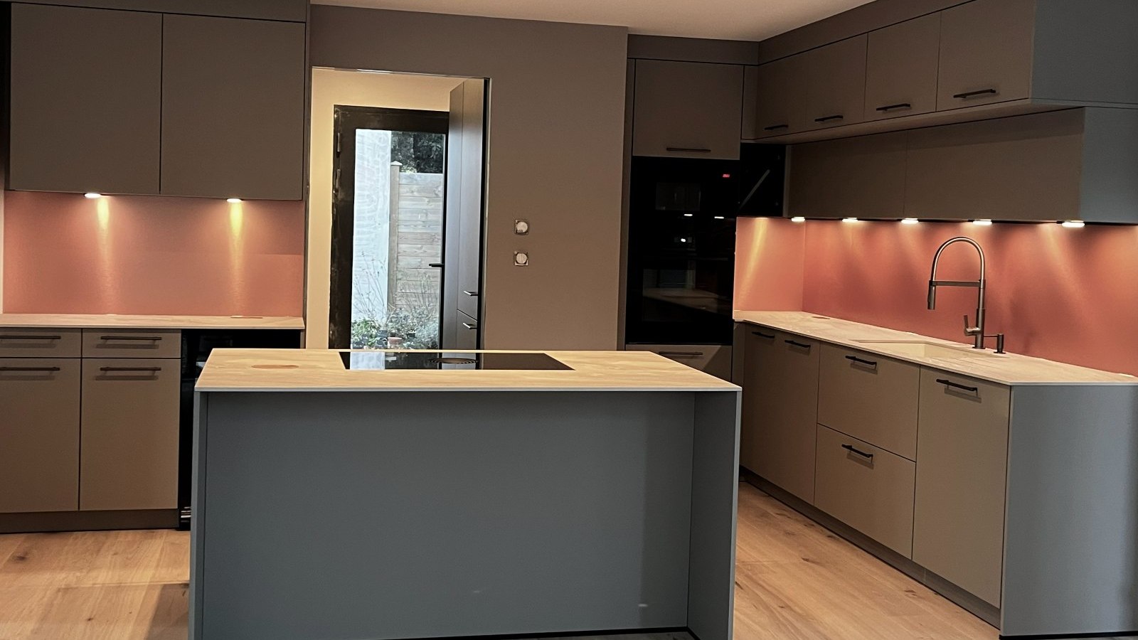 Cuisine ouverte avec îlot central, crédence cuivrée et parquet chêne, conçue par Cezope Design