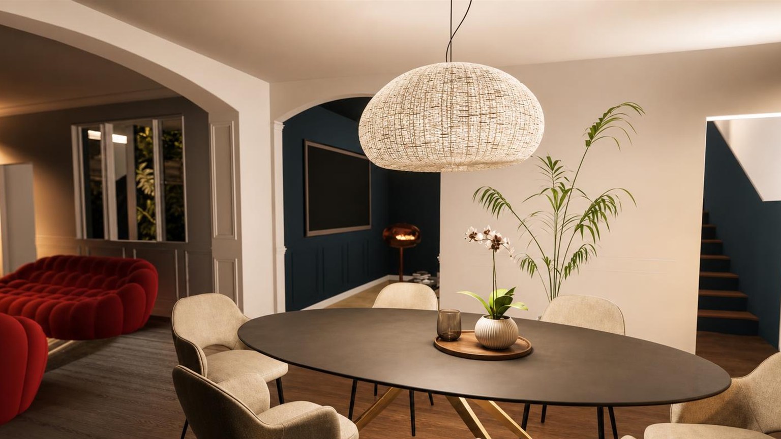 Salle à manger avec table ovale noire, suspension en fibre naturelle et perspective sur l'escalier